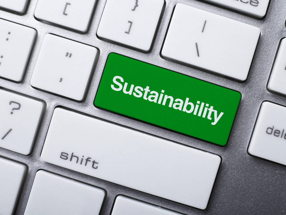 Tecla verde com a palavra “Sustainability” em um teclado branco, simbolizando inovação e compromisso ambiental nas empresas